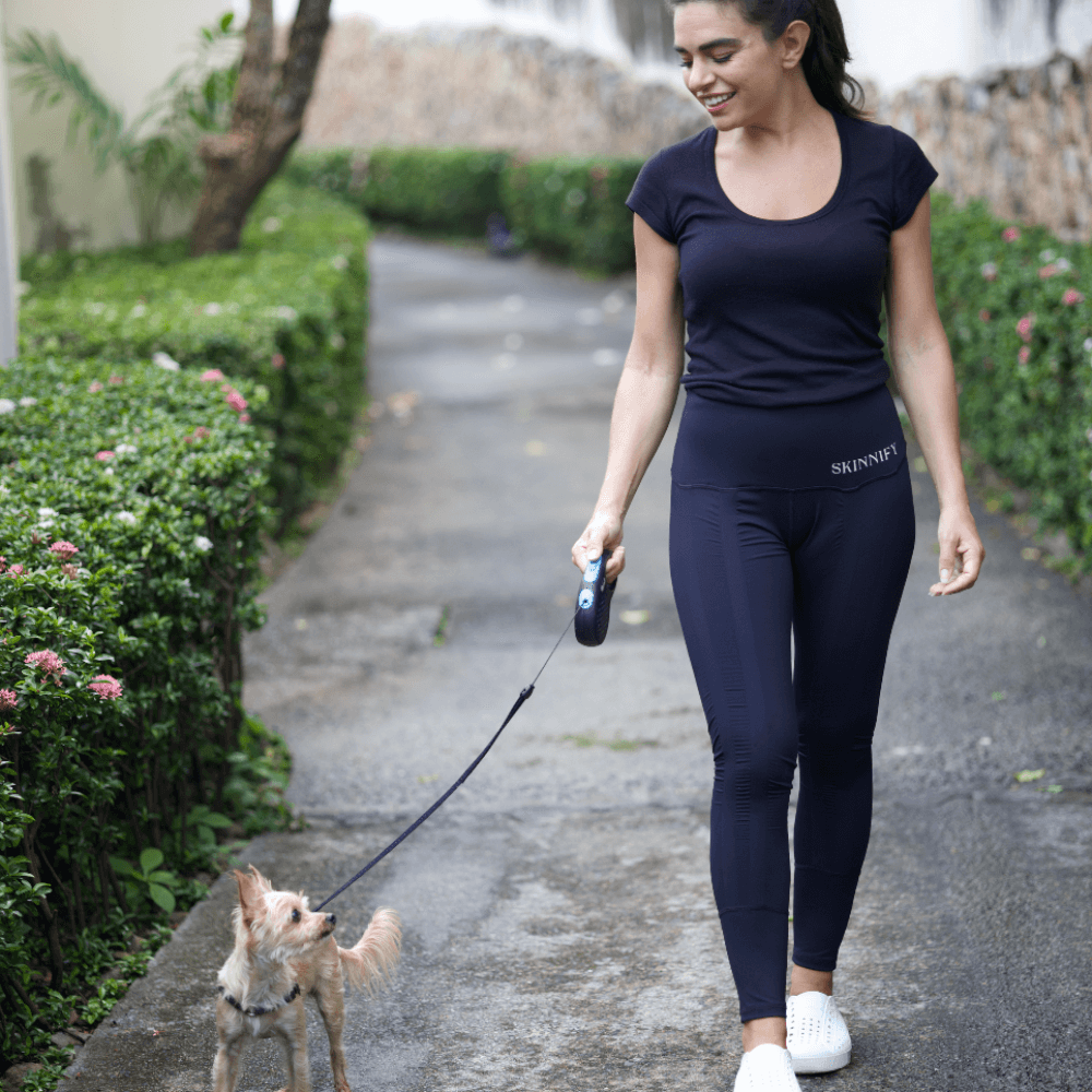 Frau trägt Abnehm Leggings beim spazieren mit dem Hund